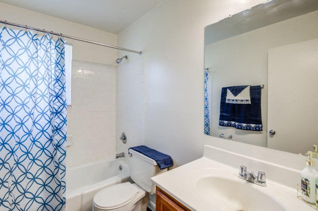 Bathroom with maple vanity and white tile surrounding tub/shower