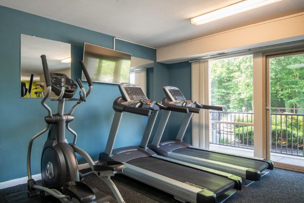the gym is equipped with cardio equipment and a large window