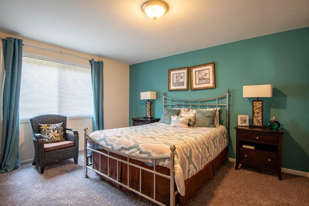 a bedroom with a bed and a chair and a window