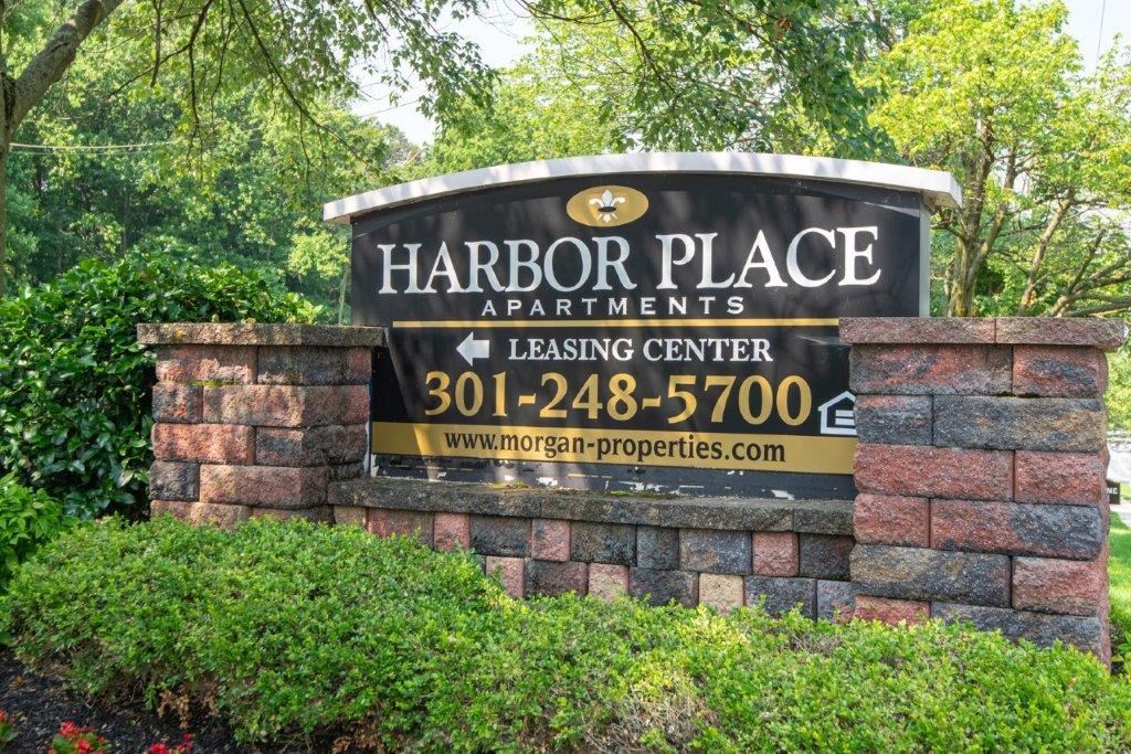a sign for the harbor place apartments leasing center is displayed on a brick wall