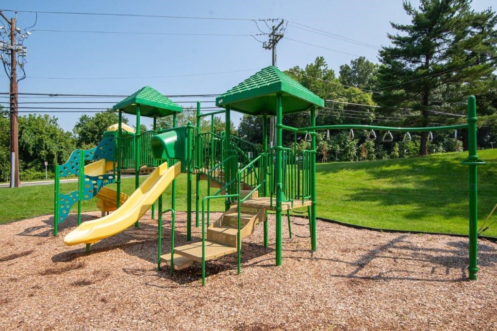 a playground with a yellow slide and green playsets