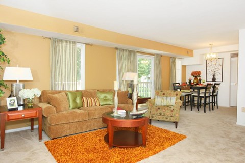A living room with a brown couch, a coffee table, and a dining table with chairs.