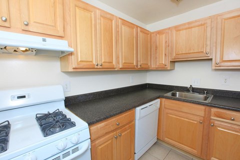 A kitchen with a white stove and wooden cabinets.