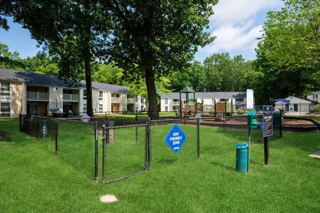a fenced in dog park with apartments in the background