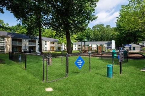 a fenced in dog park with apartments in the background