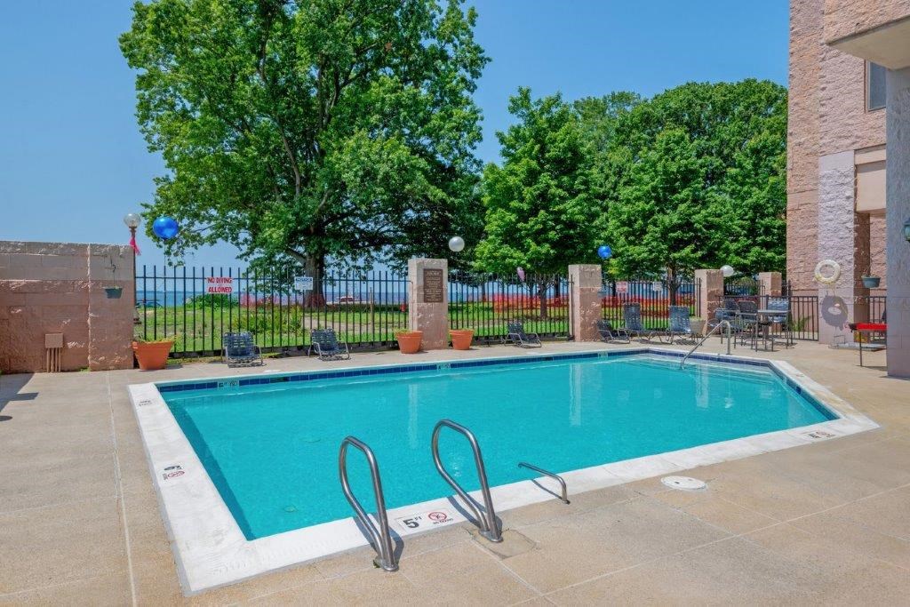 our apartments have a swimming pool with a fence and trees