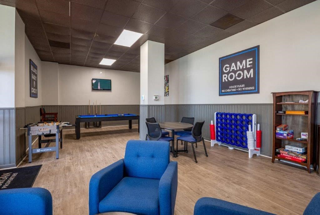 a game room with a pool table and chairs