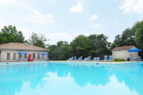 A large swimming pool with blue water and a red slide.