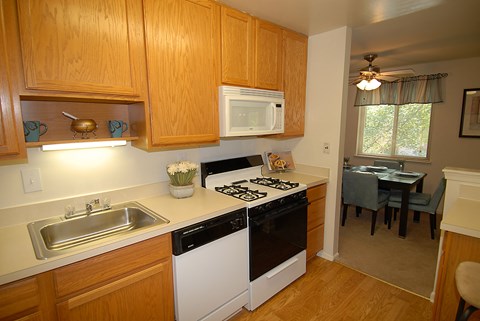 A kitchen with wooden cabinets and a white stove top oven.