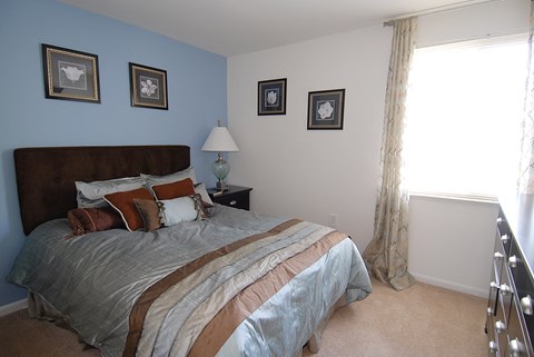 A bedroom with a large bed and a window with curtains.