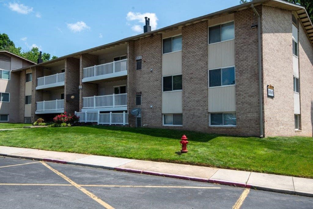a brick apartment building with a red fire hydrant in the grass
