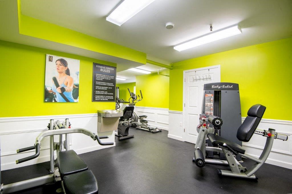 a gym with weights and other equipment in a building with yellow walls