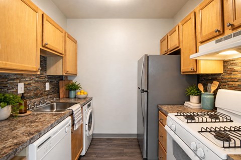 A kitchen with a black refrigerator, white stove, and wooden cabinets.