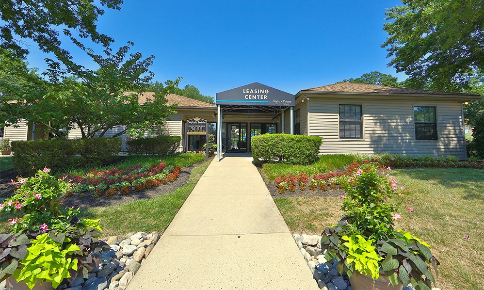 a sidewalk in front of a tan building with a sign on the front of it