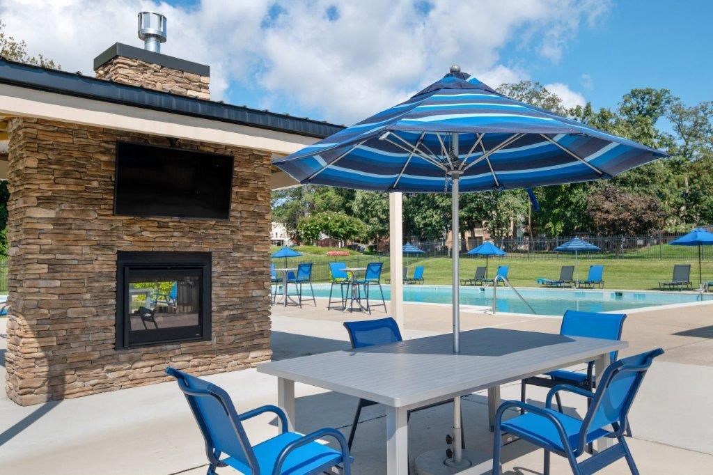 a picnic table with an umbrella and chairs near a swimming pool