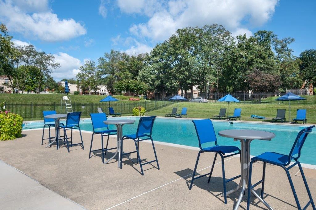 a swimming pool with blue chairs and tables next to it