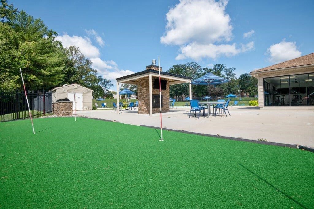 a backyard with a pool and a patio with chairs and umbrellas