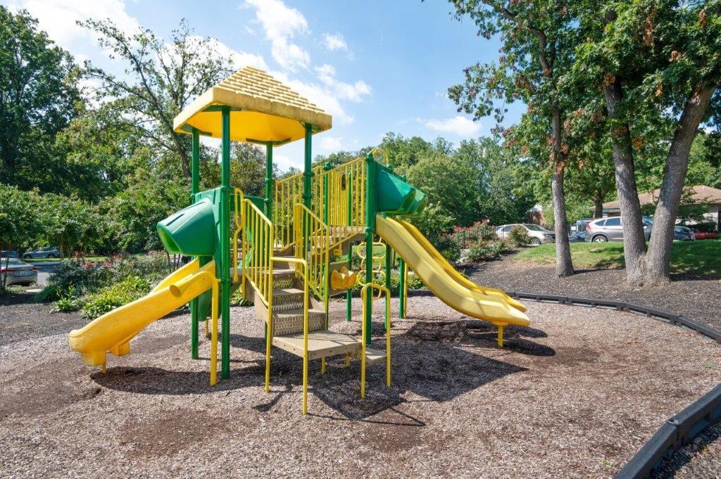 a playground with yellow and green slides in a park