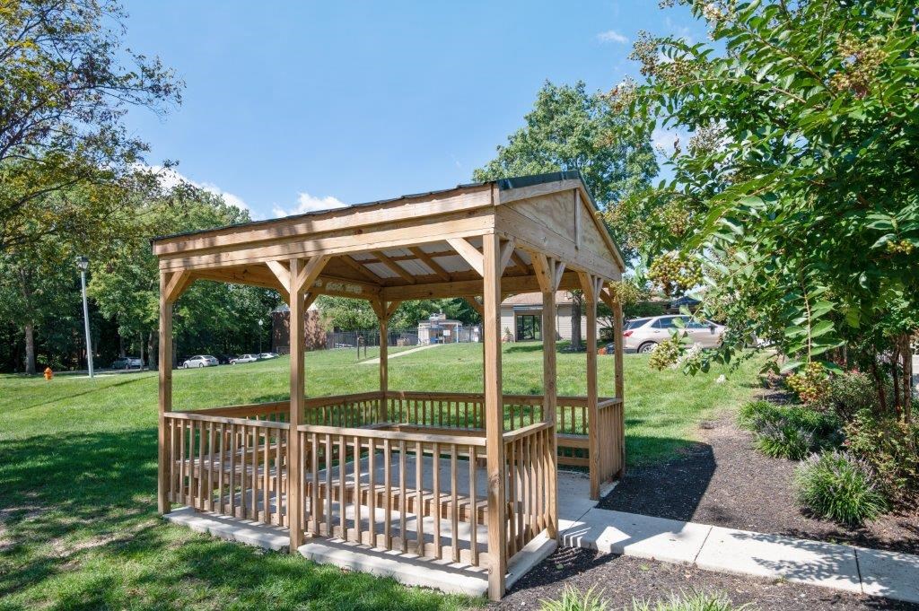 a wooden gazebo with a pond in a park