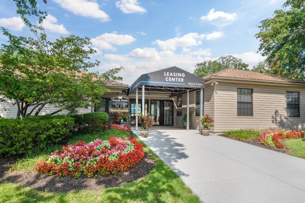 the leasing center is a tan building with a blue roof and a sidewalk