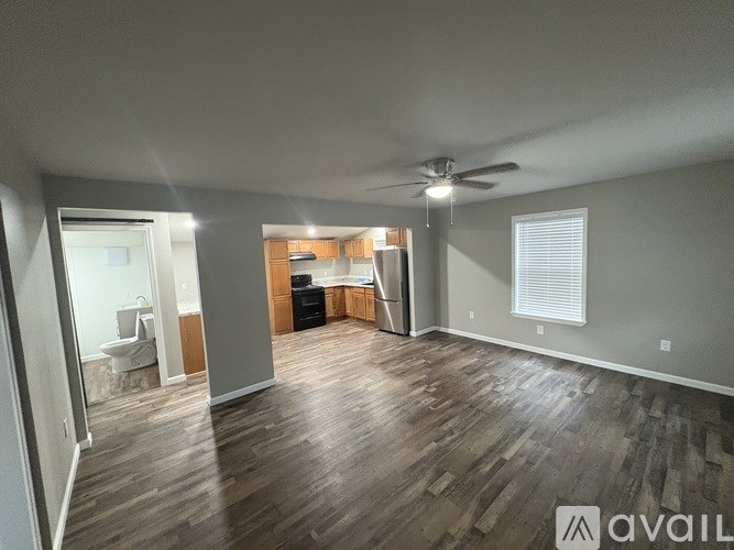 A spacious room with wooden flooring and a ceiling fan.