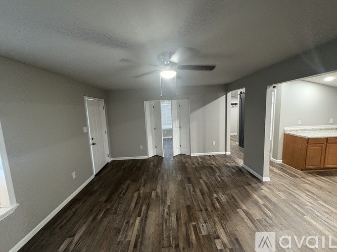 A spacious room with wooden flooring and a ceiling fan.