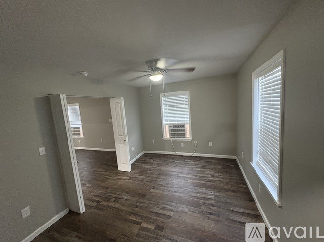A room with a ceiling fan and wooden flooring.