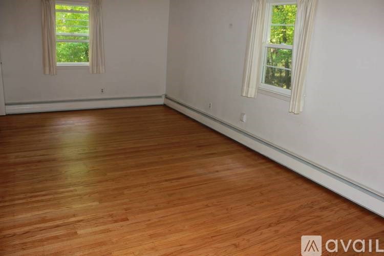 A room with wooden flooring and two windows.