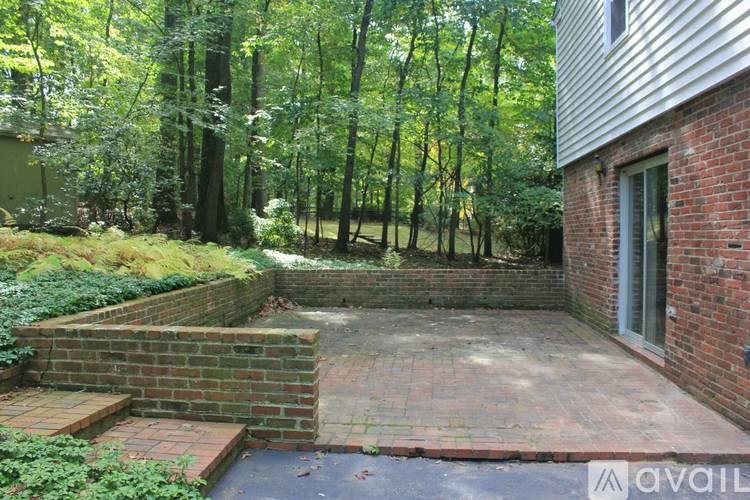A backyard with a brick patio and a brick retaining wall.