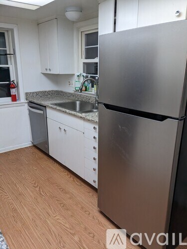A kitchen with a stainless steel refrigerator and wooden flooring.