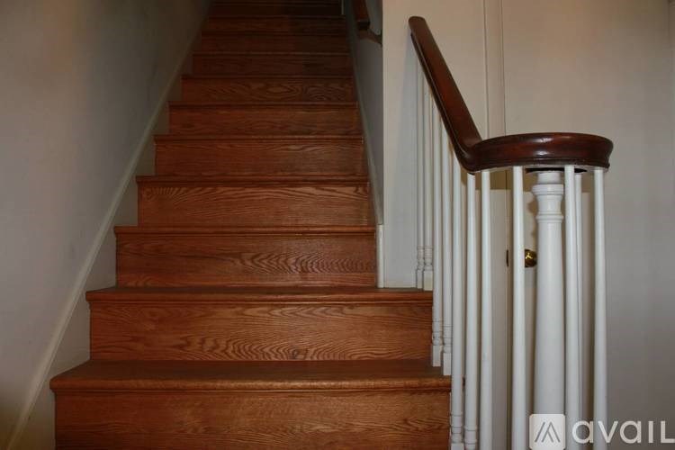 A brown wooden staircase with a white railing.