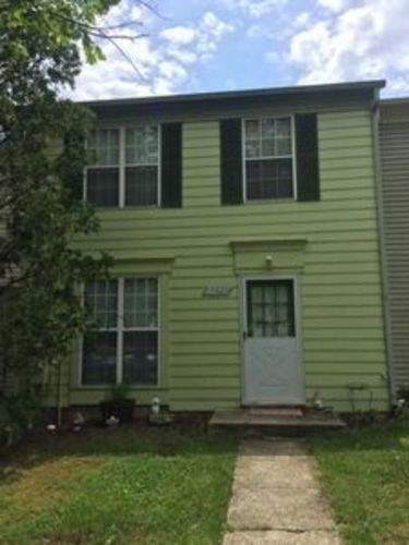 A green house with a white door and windows.