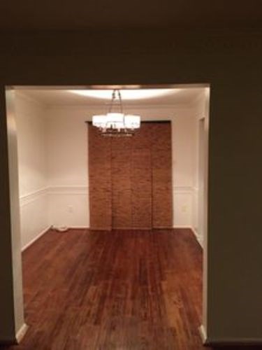 A room with a chandelier and a brick wall.