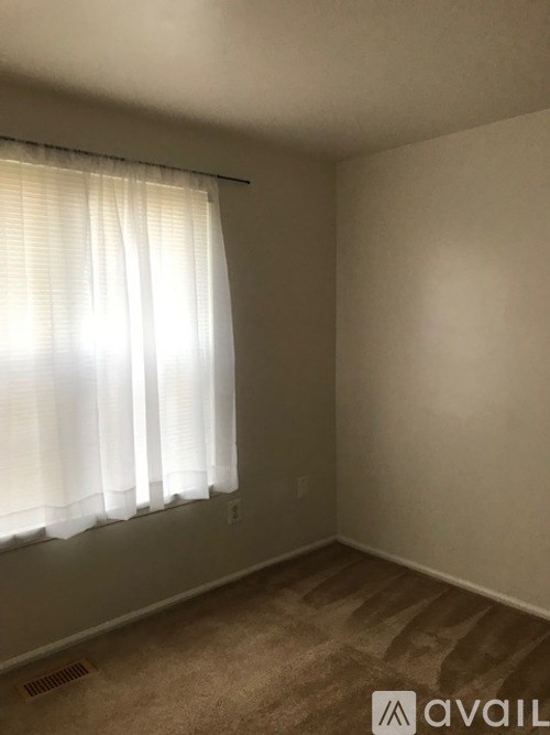 A room with a window covered by white blinds.