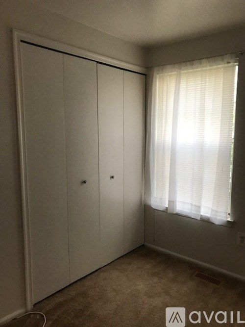 A room with a white door and a window with white curtains.