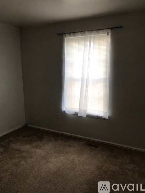 A room with a window covered by a white curtain.