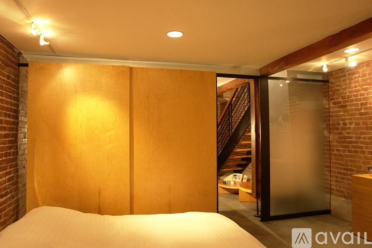 A bedroom with a bed, wooden walls, and a staircase in the background.