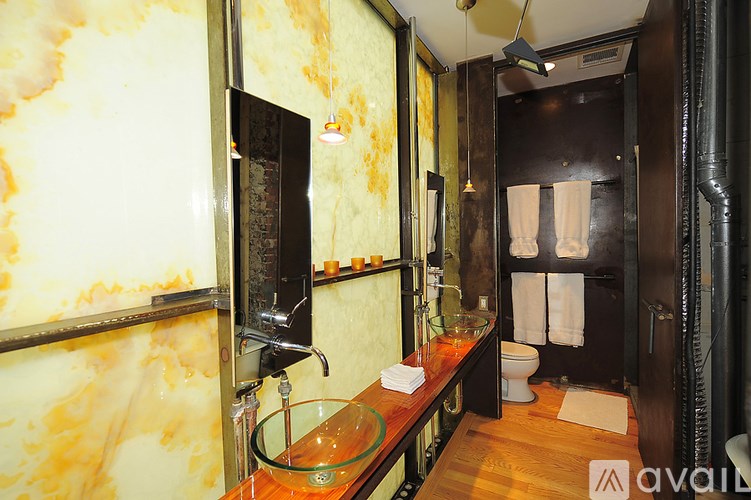 A bathroom with a marbled wall and a glass sink.