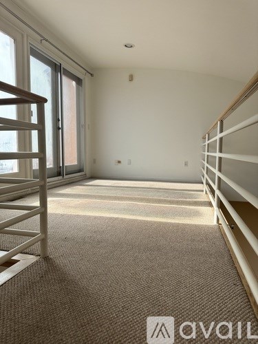 A carpeted room with a staircase and sliding glass doors.