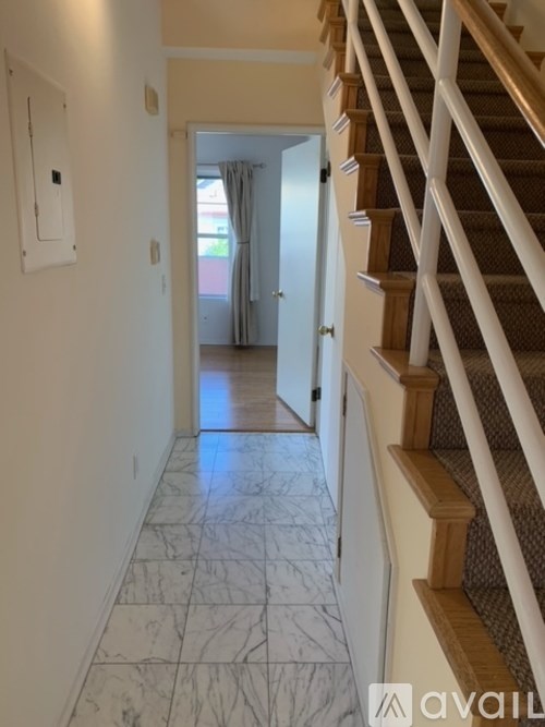 A hallway with a marble floor and a staircase on the right side.