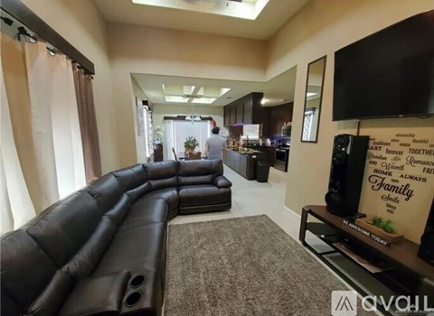 A living room with a long black couch and a flat screen TV mounted on the wall.