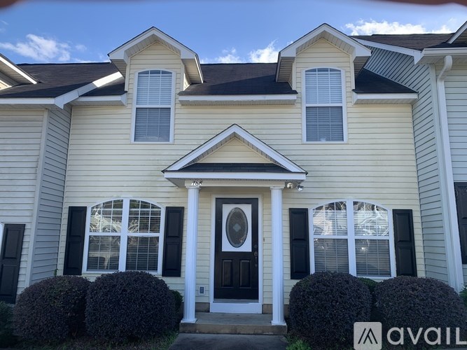 A house with a black front door and white trim is for sale.