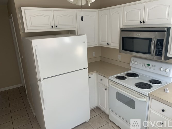 A kitchen with white appliances and cabinets.