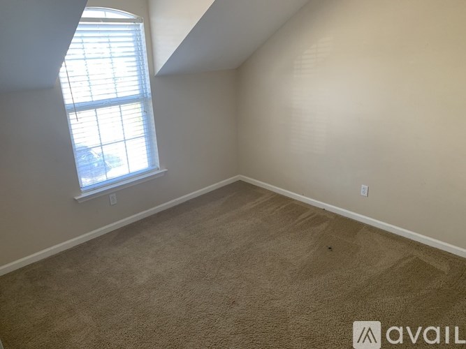 A room with a carpeted floor and a window with blinds.