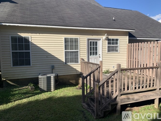 A house with a wooden deck and a window air conditioner.