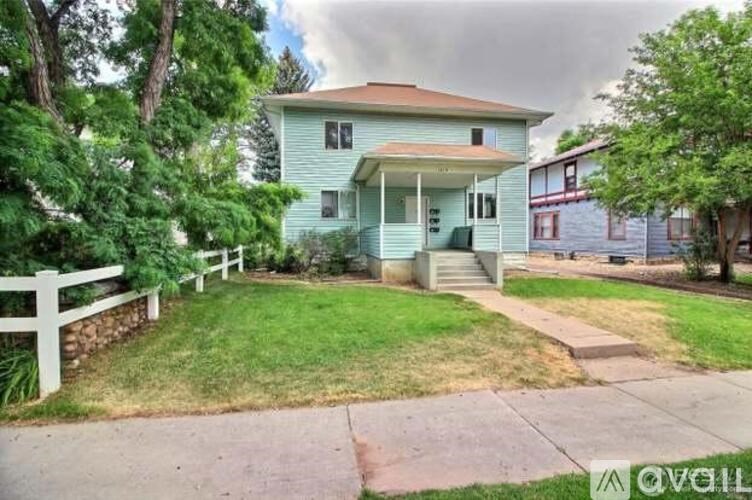 A house with a green front yard and a white fence.