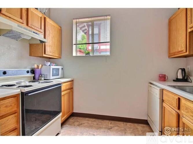 A kitchen with wooden cabinets and a window with blinds.