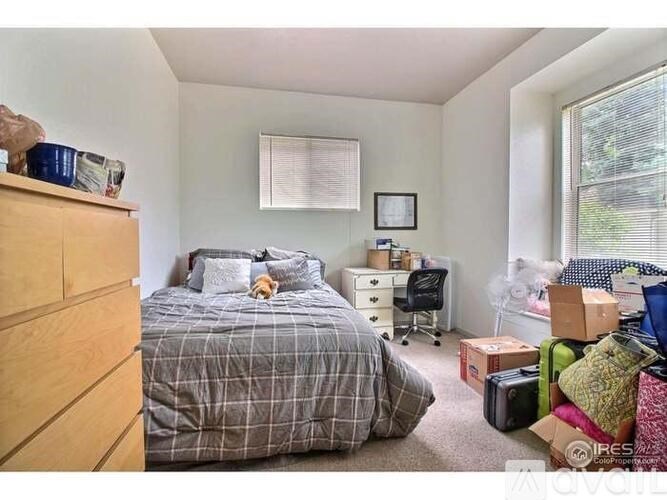 A messy bedroom with a bed, desk, and various items scattered around.