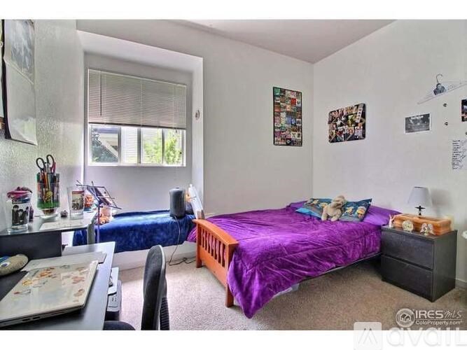 A bedroom with a purple bed and a desk with a computer.