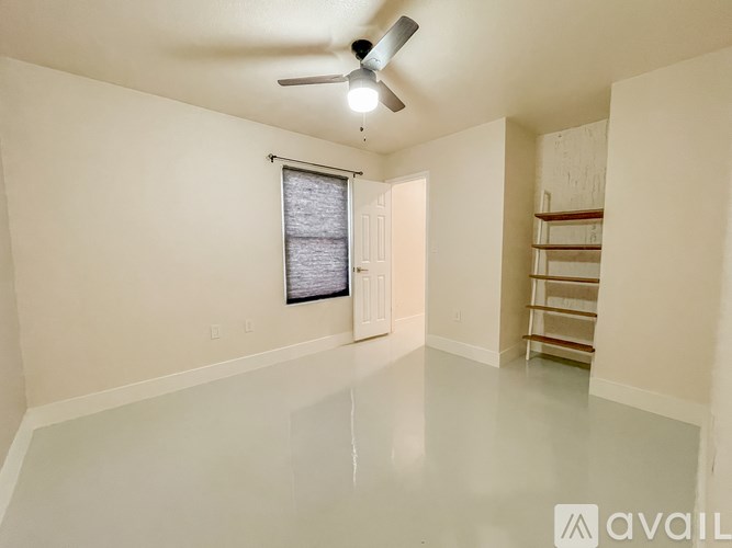 A spacious room with a ceiling fan and a window with blinds.